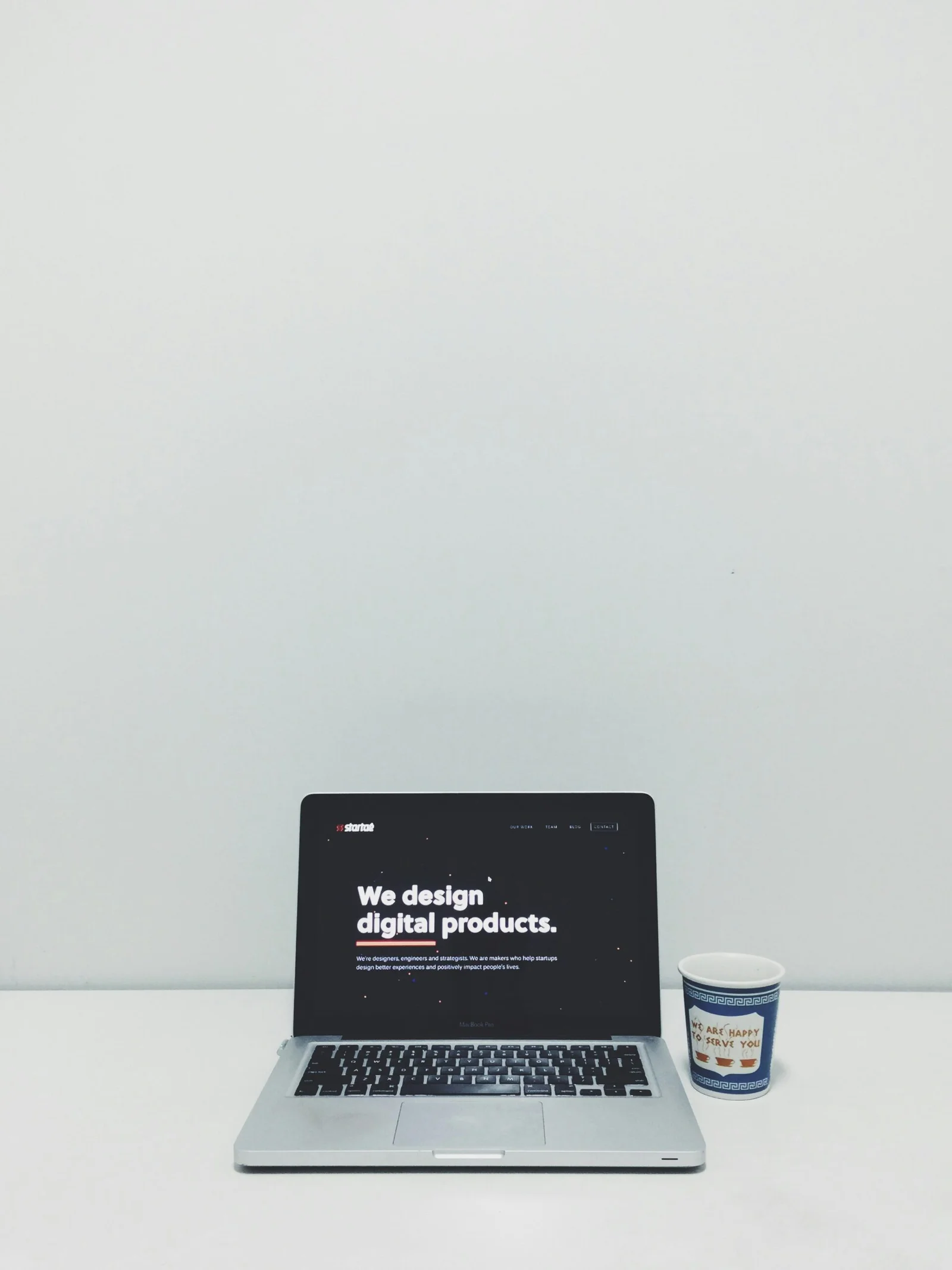 macbook pro beside white and blue plastic cup